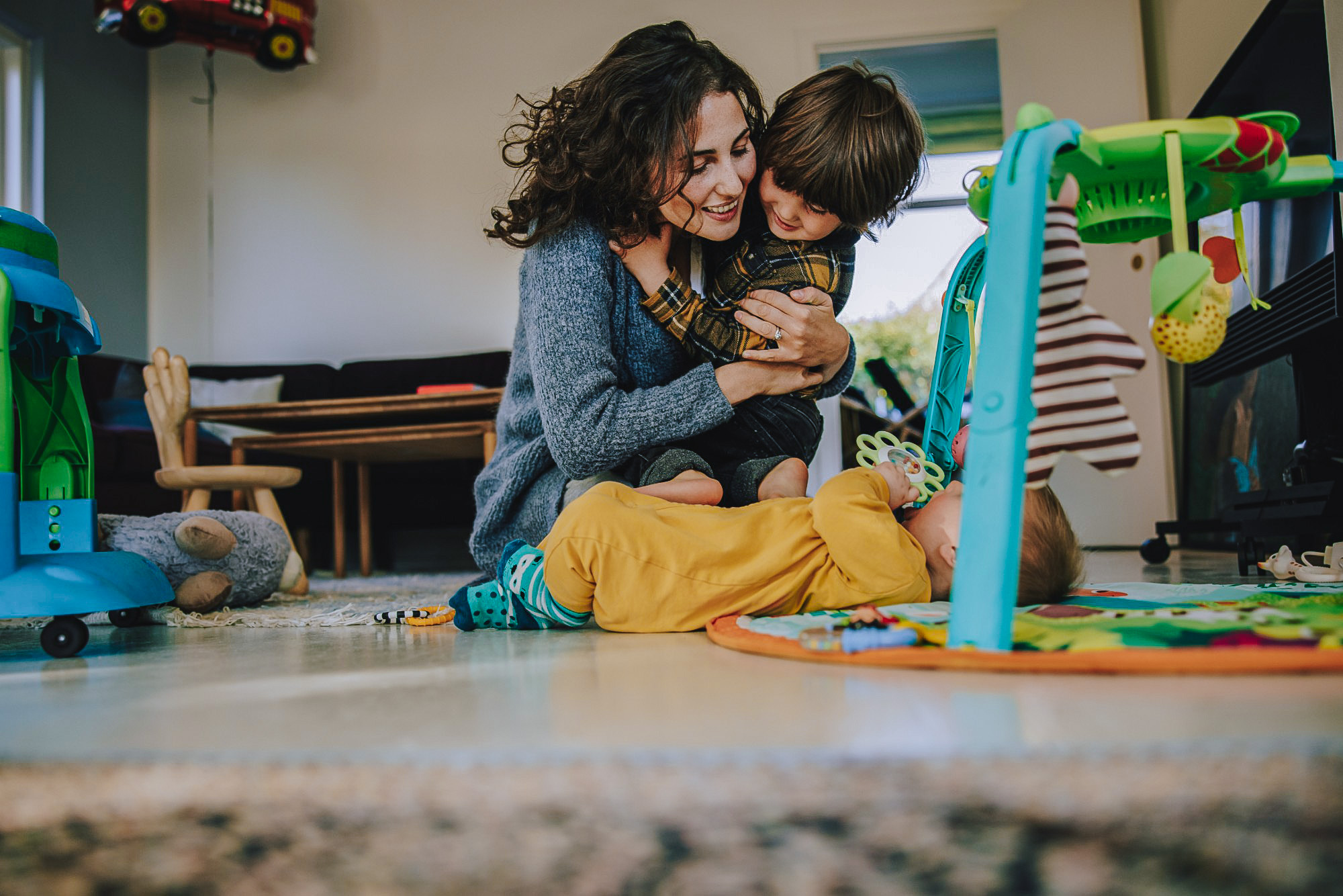 Mutter spielt mit zwei Kindern im Wohnzimmer